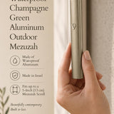 Close-up of a person holding the champagne green aluminum outdoor mezuzah, emphasizing its sleek and muted metallic finish.