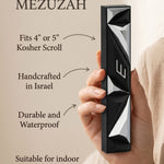 Hand-held black aluminum mezuzah with Hebrew scroll, showcasing detailed contours and traditional design.
