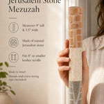 Close up of a hand holding an extra large layered Jerusalem stone mezuzah case with natural beige textures.