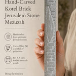 Hand presenting the handcrafted Jerusalem stone mezuzah, highlighting its textured brick pattern and authentic heritage design.