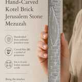 Hand presenting the handcrafted Jerusalem stone mezuzah, highlighting its textured brick pattern and authentic heritage design.