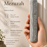 Person naturally holding the Jerusalem stone mezuzah, highlighting its texture and size for a product feature display.