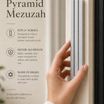 Person holding the exact modern silver pyramid mezuzah against a neutral background, demonstrating its size and design.