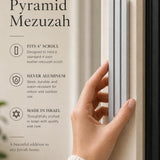 Person holding the exact modern silver pyramid mezuzah against a neutral background, demonstrating its size and design.