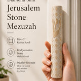 Person holding the exact Jerusalem Stone Mezuzah with cream color, carved diamond pattern, and gold Shin, in a natural, balanced composition.
