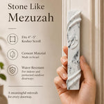 Person holding the exact stone-like mezuzah in a natural pose, emphasizing size and material, for a premium store presentation.