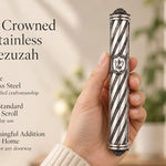 A person holding a premium silver-toned spiral stainless steel mezuzah featuring ornate end caps and a traditional Shin letter.