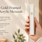 Handheld Lumen mezuzah featuring a gold frame and white acrylic finish in a styled editorial setting.
