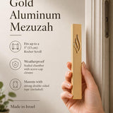Person naturally holding the Eternal Flame Gold Aluminum Mezuzah at realistic scale, showcasing its design and size for e-commerce display.