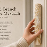 Person holding a large olive branch Jerusalem stone mezuzah at realistic scale, emphasizing craftsmanship and design in a premium editorial style.