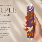 Hand-holding purple Dove of Peace mezuzah with white dove motif and orange accents, placed beside editorial text for premium presentation.