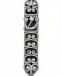 High-resolution image of a pewter Ram Mezuzah with curved ram horn shapes, accented with clear sequins, set against a bright white studio background with a subtle reflection.