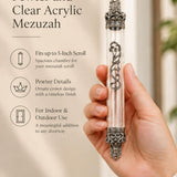 Handheld portrait of the Regal Crown Pewter and Clear Acrylic Mezuzah mezuzah cover, with a transparent acrylic chamber framed by silver-toned pewter crown ends, dark recessed details and curling front scrollwork clearly visible beside the product name and illustrated features of this distinctive Jewish doorway design