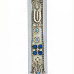 Petite regal Mezuzah with blue embellishments on a metal base, displayed on a white studio background with soft reflection, detailed craftsmanship.