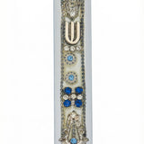 Petite regal Mezuzah with blue embellishments on a metal base, displayed on a white studio background with soft reflection, detailed craftsmanship.