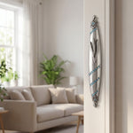Hyper-realistic image of a polished pewter mezuzah with blue gemstones mounted on the right side of an interior doorway in a stylish home setting.
