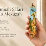 Savannah Safari Fimo Mezuzah mezuzah cover held upright in one hand, showing a pale blue Fimo body with tall yellow giraffes, a zebra, spotted animals, green scenery and a gold-colored Hebrew Shin beneath decorative brass fittings beside the product name and illustrated design features in a wide social-sharing graphic for decorative Jewish home Judaica