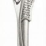 Upscale photo of an engraved pewter Mezuzah 4.5 inches tall with Hebrew script and crowned Shin with blue stones, on a polished white surface.