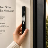 Large black acrylic mezuzah cover mounted vertically on a light-colored front doorpost, showing its slim profile and contrasting silver Shin