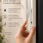 Clear acrylic mezuzah cover displayed vertically on a front doorpost, showing its large seven-inch scale and transparent rectangular body
