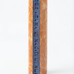 Shema Mezuzah crafted from Jerusalem stone with inlaid glass strip bearing Hebrew prayer, mounted on a white studio background with subtle reflection.
