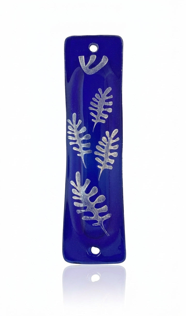 Silver glass mezuzah with intricate engraved details, Hebrew letters, and decorative motifs, mounted on a white background with a soft reflection.