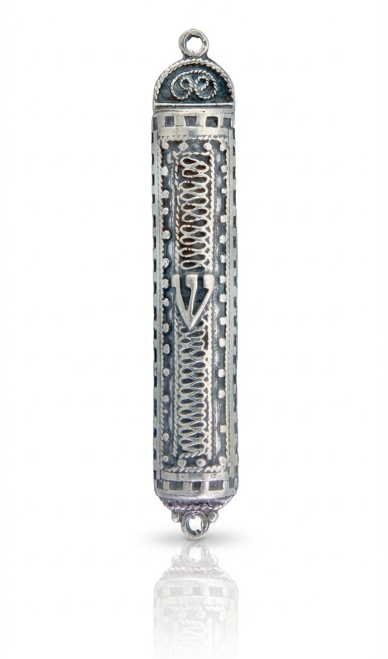 Sterling silver filigree accordion mezuzah with intricate design and Hebrew engravings, displayed on a white studio surface with soft reflection.