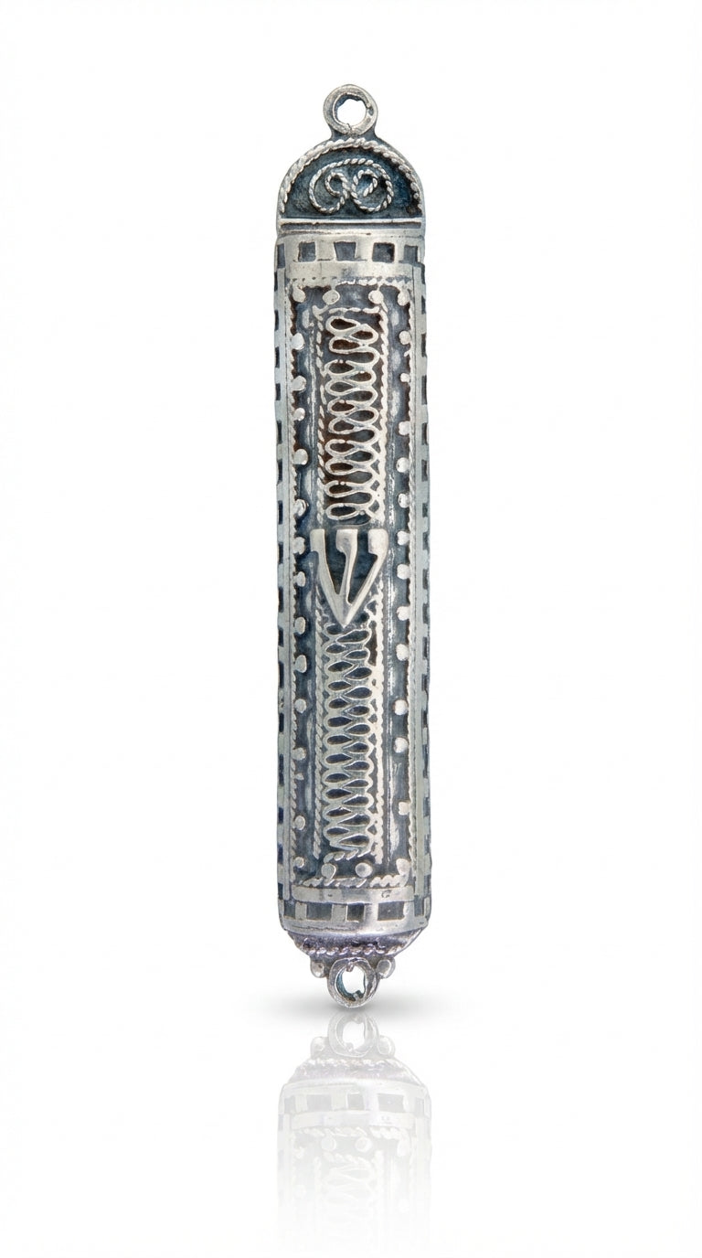 Sterling silver filigree accordion mezuzah with intricate design and Hebrew engravings, displayed on a white studio surface with soft reflection.