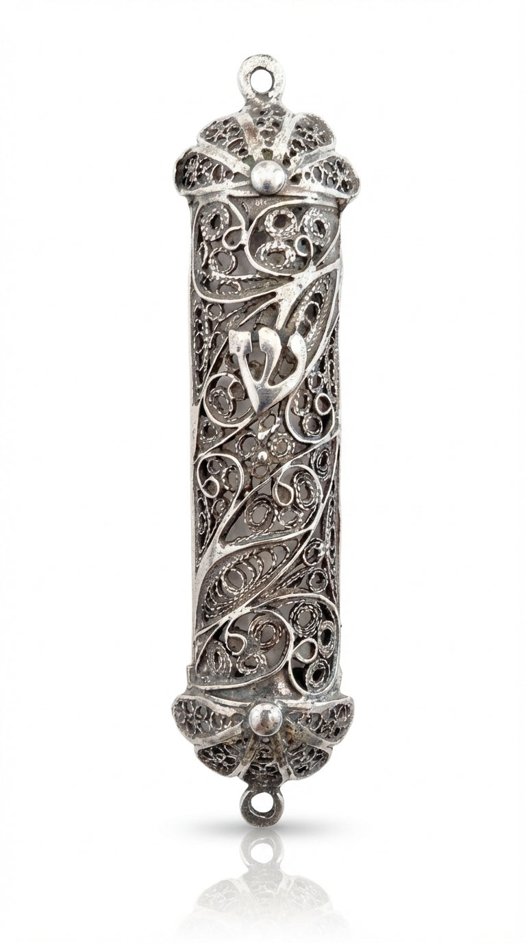 Elegant handmade silver mezuzah with intricate filigree, transparency to view parchment, and traditional Hebrew engravings on a white background.