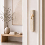 Small Modern Cream Jerusalem Stone Mezuzah installed on a white entryway doorpost, with its pale stone face, gently rounded shape, and gold Shin clearly visible against the light trim