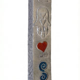 Petite Moroccan style pewter mezuzah with Hebrew engravings and decorative motifs, displayed on a white studio background with subtle reflection.