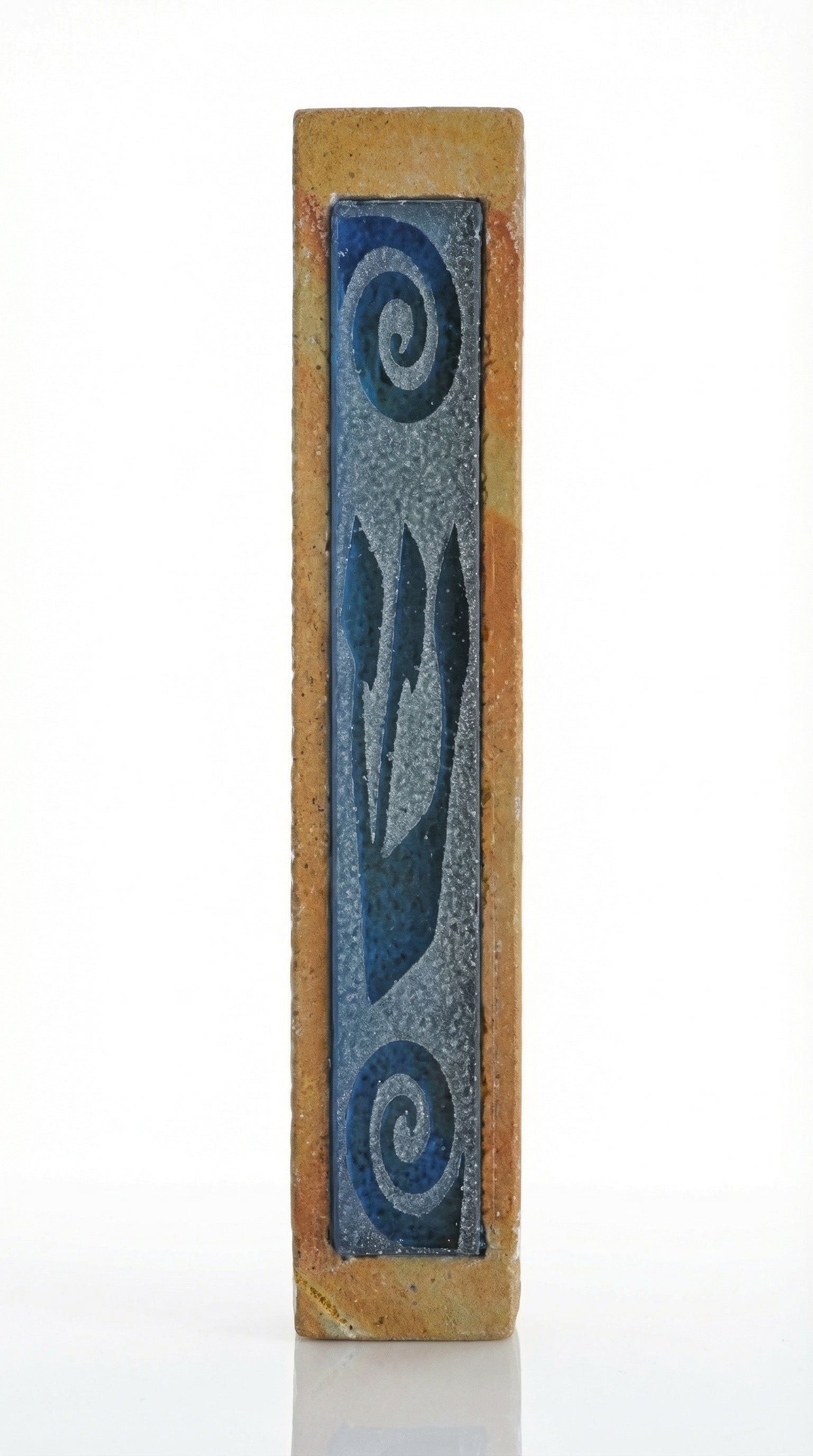 Stone and glass mezuzah with blue frosted glass Shin and swirl design, mounted on a white studio surface with soft reflection.