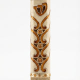 Close-up of a brass Sunrise Mezuzah with detailed Hebrew engravings, shown on a white studio background with a subtle reflection.