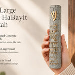 Close up of a hand holding a large gray stone-textured mezuzah featuring a gold Shin and Birkat HaBayit engraving.