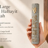 Close up of a hand holding a large gray stone-textured mezuzah featuring a gold Shin and Birkat HaBayit engraving.