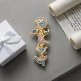 Artistic flat lay of The Shalom Birds Mezuzah on a concrete surface, with a gift box and scroll, highlighting craftsmanship and design.