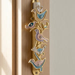 Close-up of The Shalom Birds Mezuzah on a minimalist interior door frame, featuring pewter material with intricate engravings and enamel details.
