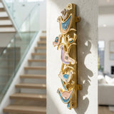 Side perspective of The Shalom Birds Mezuzah attached to a textured wall near a modern staircase, showing dimensions and details.