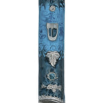 Pewter mezuzah with enamel paint, featuring a floating leaf on a blue background, displayed on a white studio surface with soft reflection.
