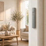 Timeless Raised Silver Shin Gray Cement Mezuzah mounted vertically on a residential doorpost, showing the slim gray cement case and sculptural silver-tone Shin in a bright modern home entrance
