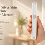 Close up of a hand holding an opaque white mezuzah case with silver Hebrew Shin detailing designed for outdoor use.