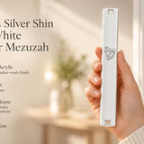 Close up of a hand holding an opaque white mezuzah case with silver Hebrew Shin detailing designed for outdoor use.