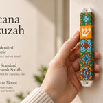 A hand holds the colorful ceramic Toscana Mezuzah case featuring orange, green, and blue floral motifs with a central Hebrew Shin.