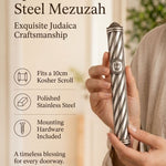 A hand displays an ornate silver-toned stainless steel mezuzah case with spiral bands and decorative end caps.