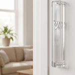 Modern clear Lucite mezuzah case with silver Shin, mounted inside a stylish doorway handle on a clean doorframe.