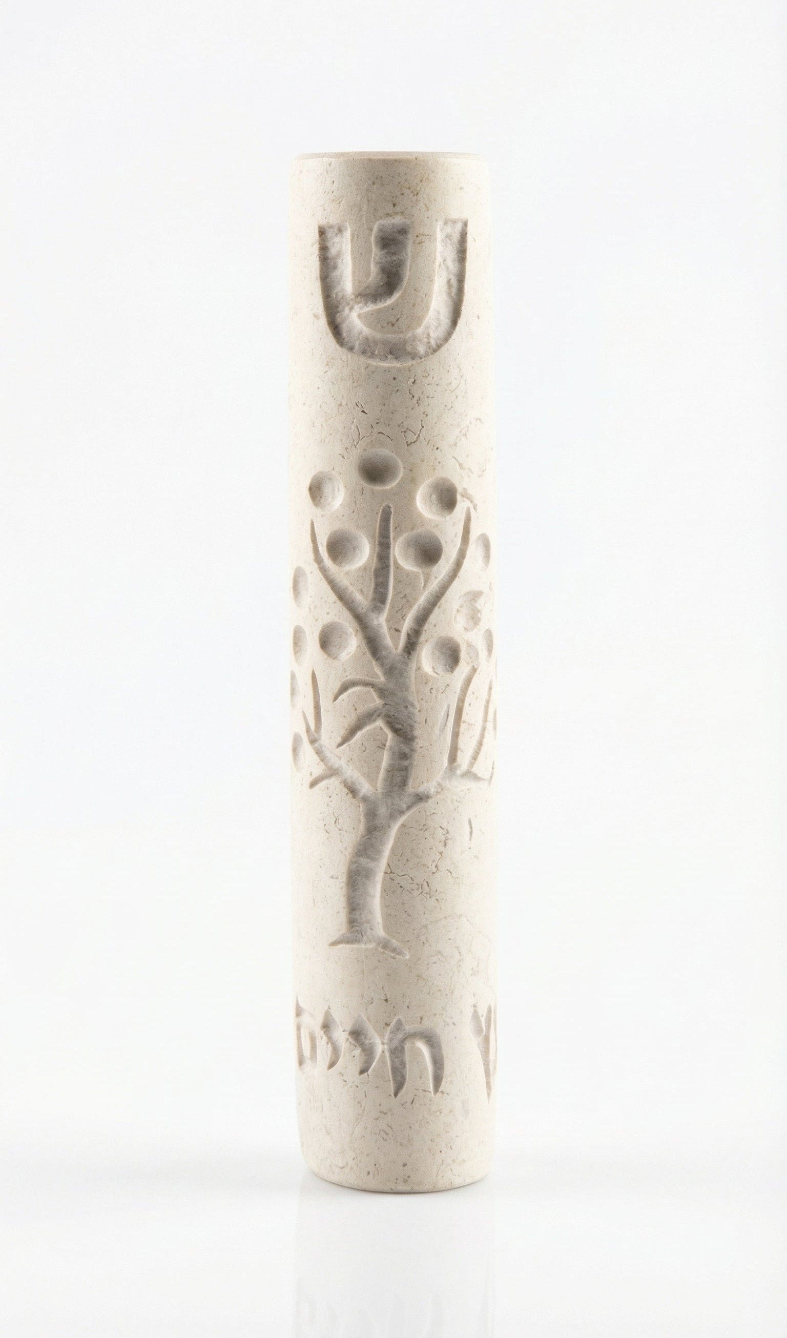 Cream Jerusalem stone Mezuzah with intricate design and Hebrew inscription, displayed vertically on a white studio surface with a soft reflection.