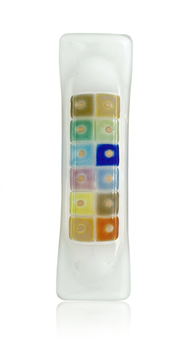 Contemporary glass mezuzah with fused-glass checkerboard pattern, 4.5 inches tall, mounted on a polished white studio surface with light reflection.