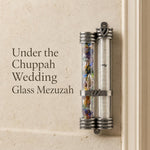 Wedding glass mezuzah with dual-tube design for broken glass and scroll display, mounted on doorway with silver-toned frame.