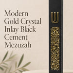 Close view of a unique modern black cement mezuzah case featuring a raised gold Shin above a long inset panel filled with reflective golden crystal and glass pieces, styled against a simple neutral background for a bold contemporary Judaica look