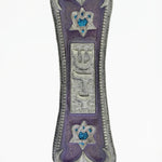 Elegant pewter mezuzah with violet pearlescent face, framed Hebrew letter Shin, Star of David symbols, on a white studio background with soft reflection.